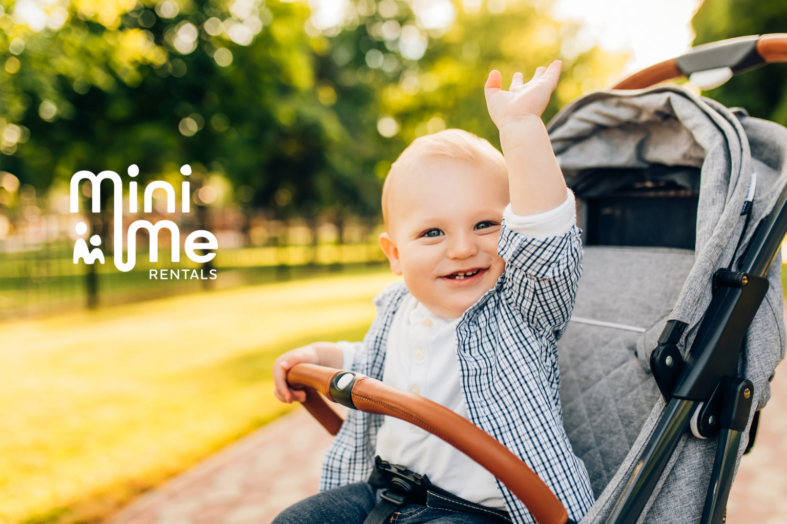 A baby in a stroller looking happy to be in a mini me rentals product. The brand logo is overlaid